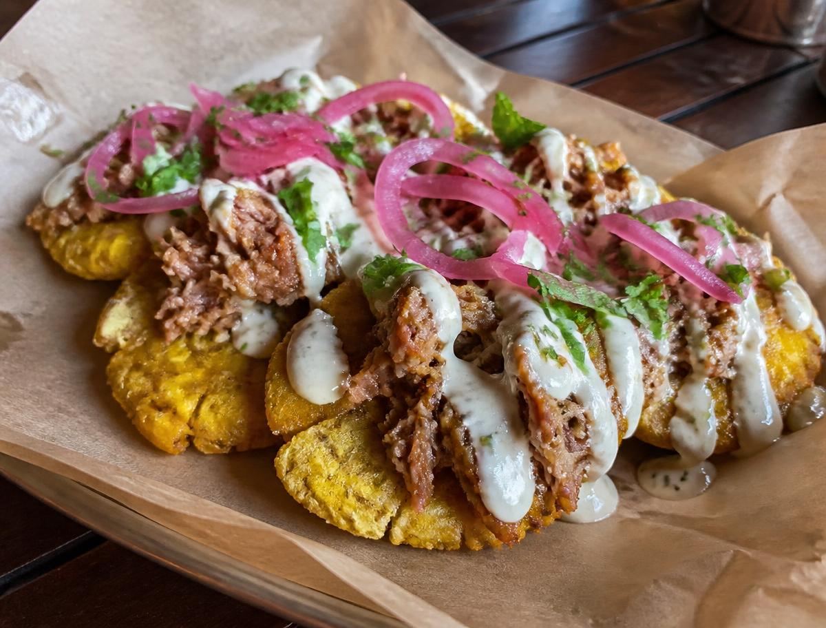 Loaded tostones topped with mojo pork, garlic crema, cilantro and pickled red onion